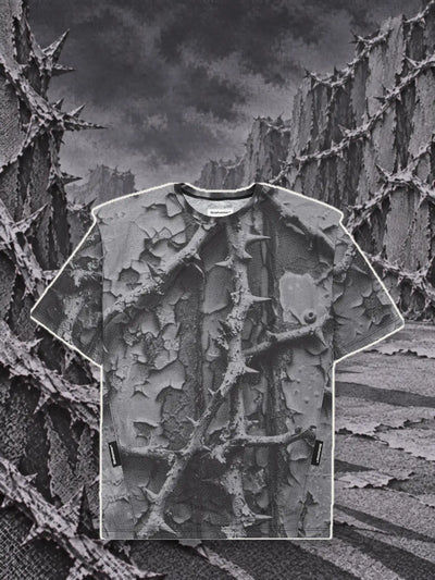 Den grå t-shirten Bloodrose Dark, med en kant av ljust papper, bland murar av grå törnsnår i relief.