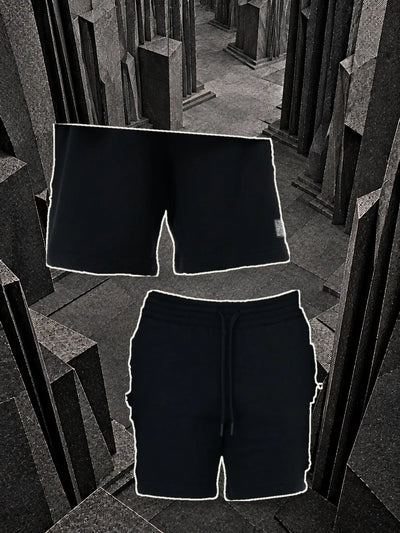 De svarta bermudashortsen Classic Black sedda bakifrån, hängda i en tråd, och framifrån med dragsnöret, bland block av mörkt papper.