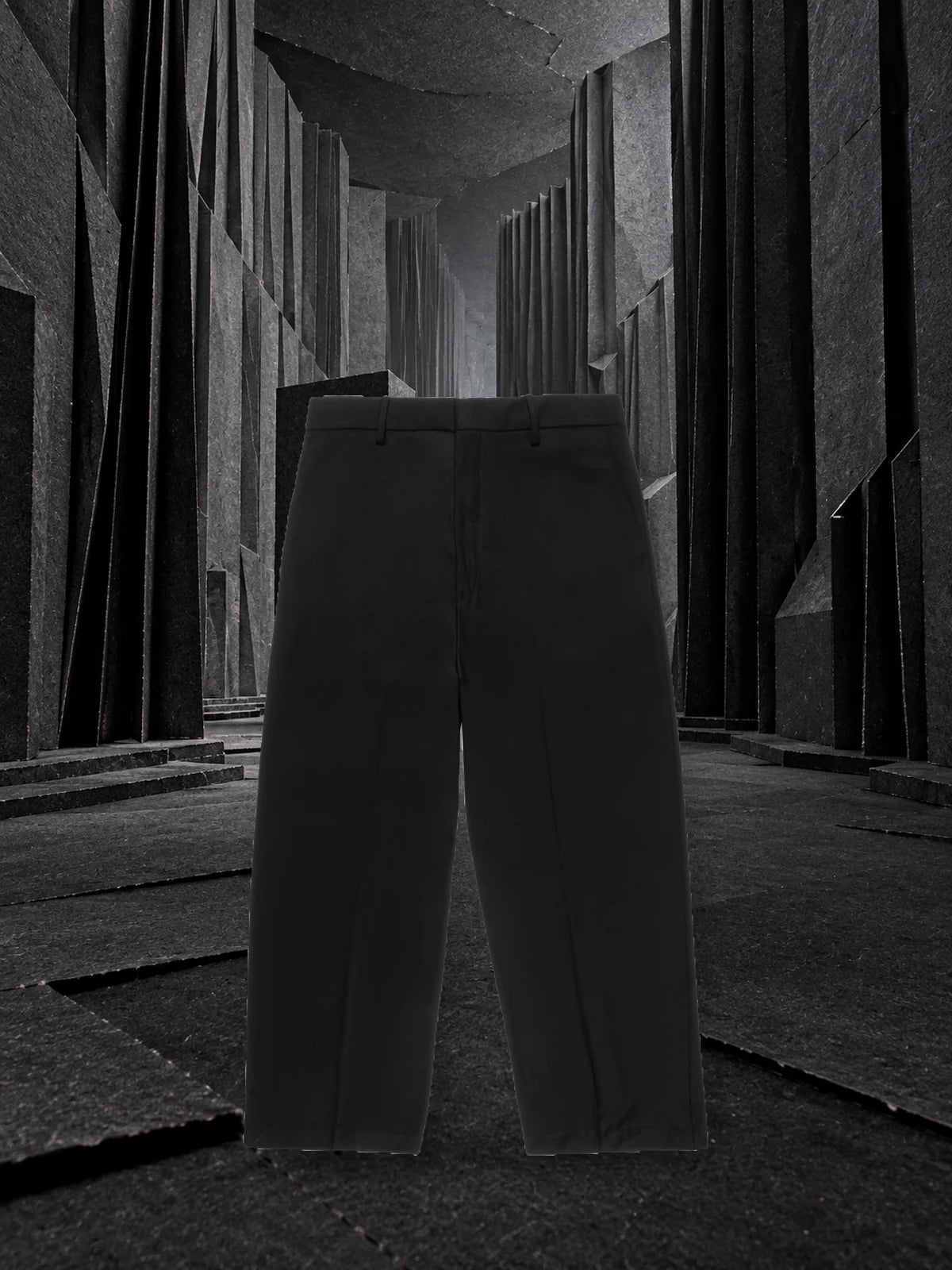 I pantaloni neri Classic in piedi in un corridoio di carta nera piegata a pieghe profonde, con una luce grigia dal fondo.