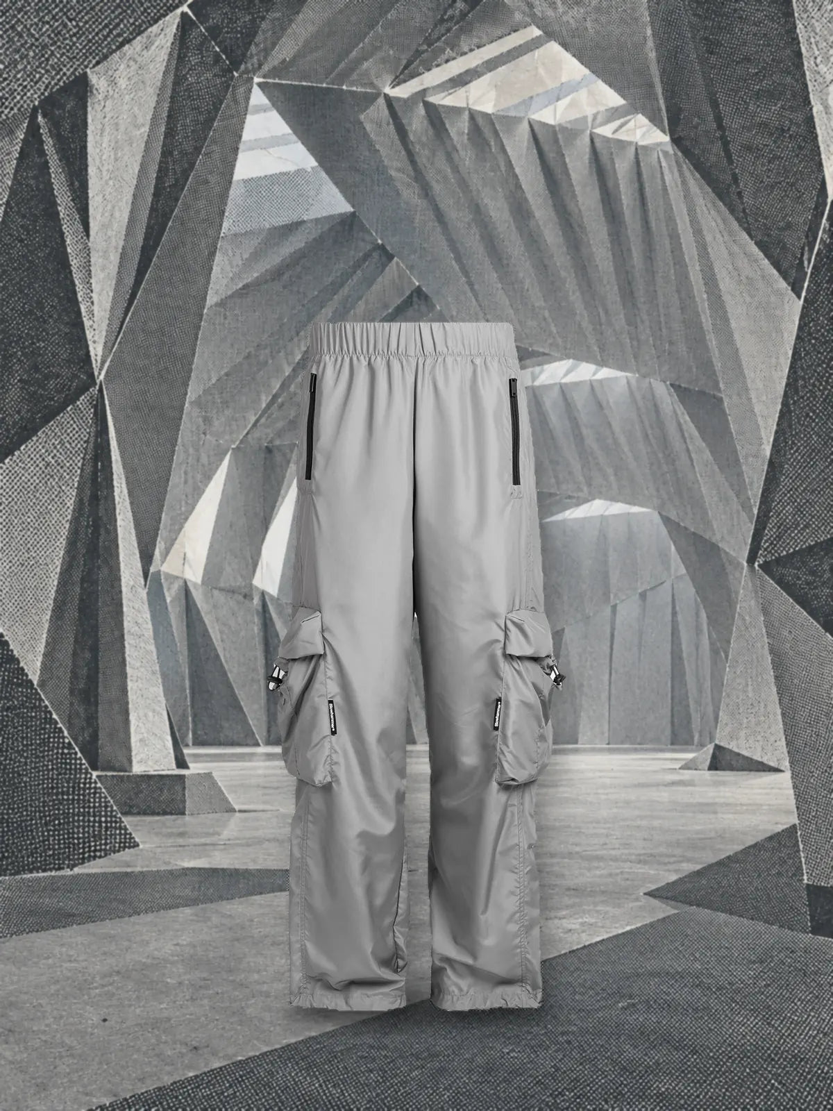 The grey Coloured cargo trousers standing in a hangar of folded silver paper, printed in halftone.