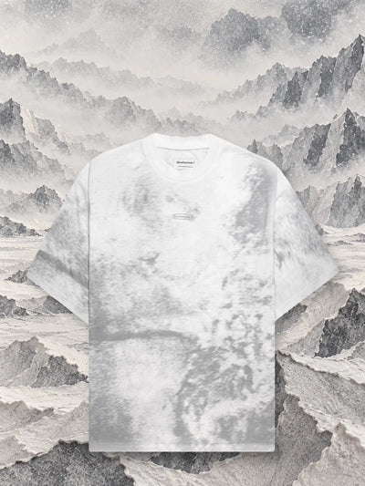 Den grå t-shirten Grey Noise framför åsar av grått och vitt papper som tonar bort i dimman.