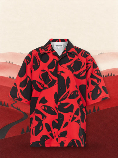 Den röda och svarta kortärmade skjortan Strand Red bland kullar av rött papper, under en ljus himmel.