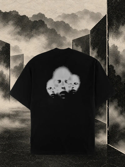 Den svarta t-shirten Triodrome bland paneler av mörkt papper och sandfärgad dimma.